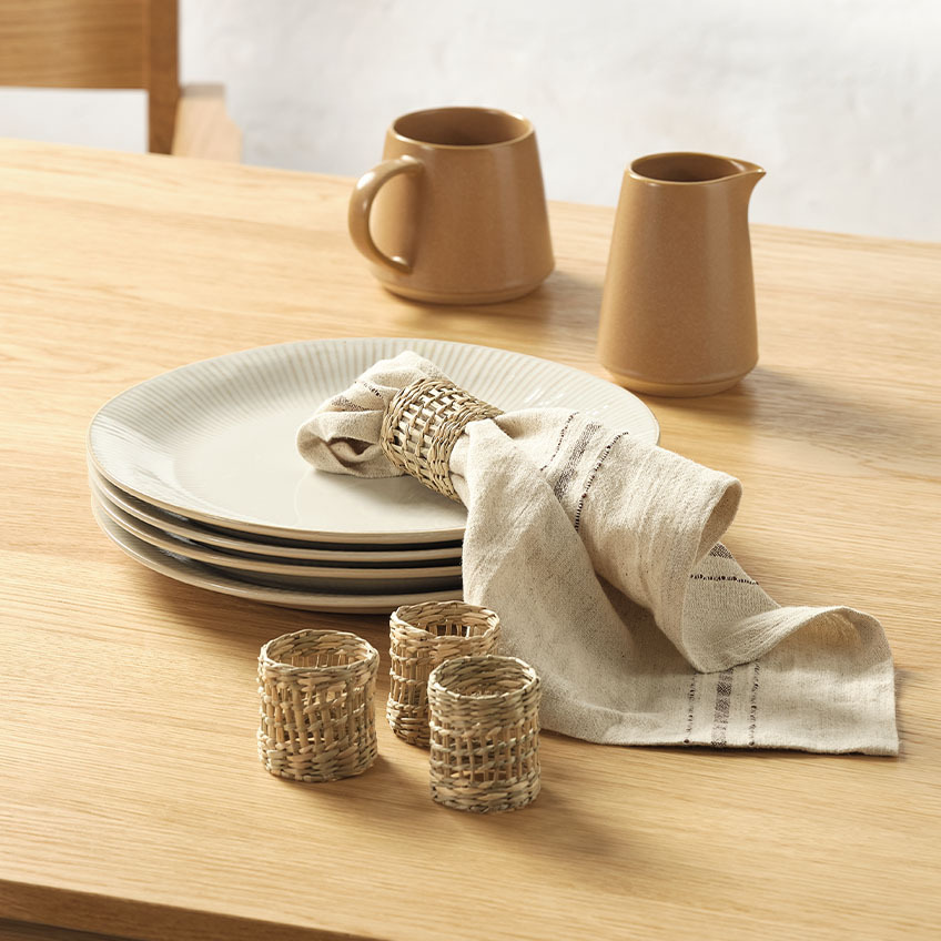 Γαλατιέρα, πετσέτα φαγητού και δαχτυλίδια πετσέτας πάνω σε τραπέζι τραπεζαρίας
