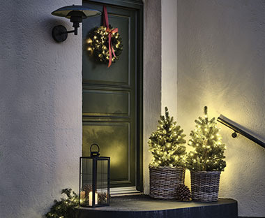 Χριστουγεννιάτικος στολισμός με φανάρια και δεντράκια με λαμπάκια στην είσοδο πόρτας