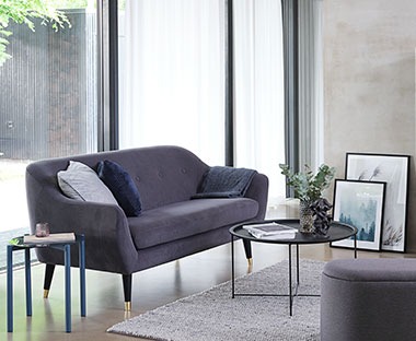 Καναπές με κοτλέ υφή σε σκούρο γκρι χρώμα σε σαλόνι μπροστά από την μπαλκονόπορτα