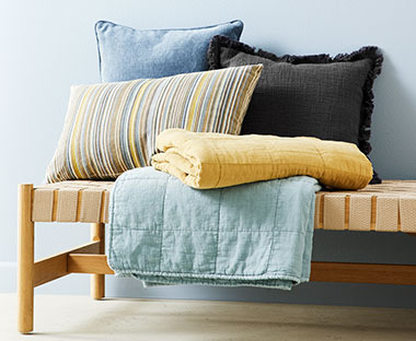 Διακοσμητικά μαξιλάρια σε διάφορα χρώματα και σχέδια και κάλυμμα κρεβατιού πάνω σε daybed