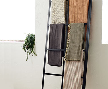 Ριχτάρια και καλύμματα κρεβατιού σε διάφορα χρώματα κρεμασμένα σε διακοσμητική σκάλα