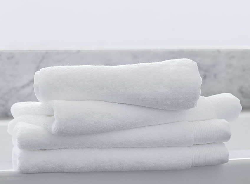 Λευκές πετσέτες μπάνιου σε στοίβα στο μπάνιο