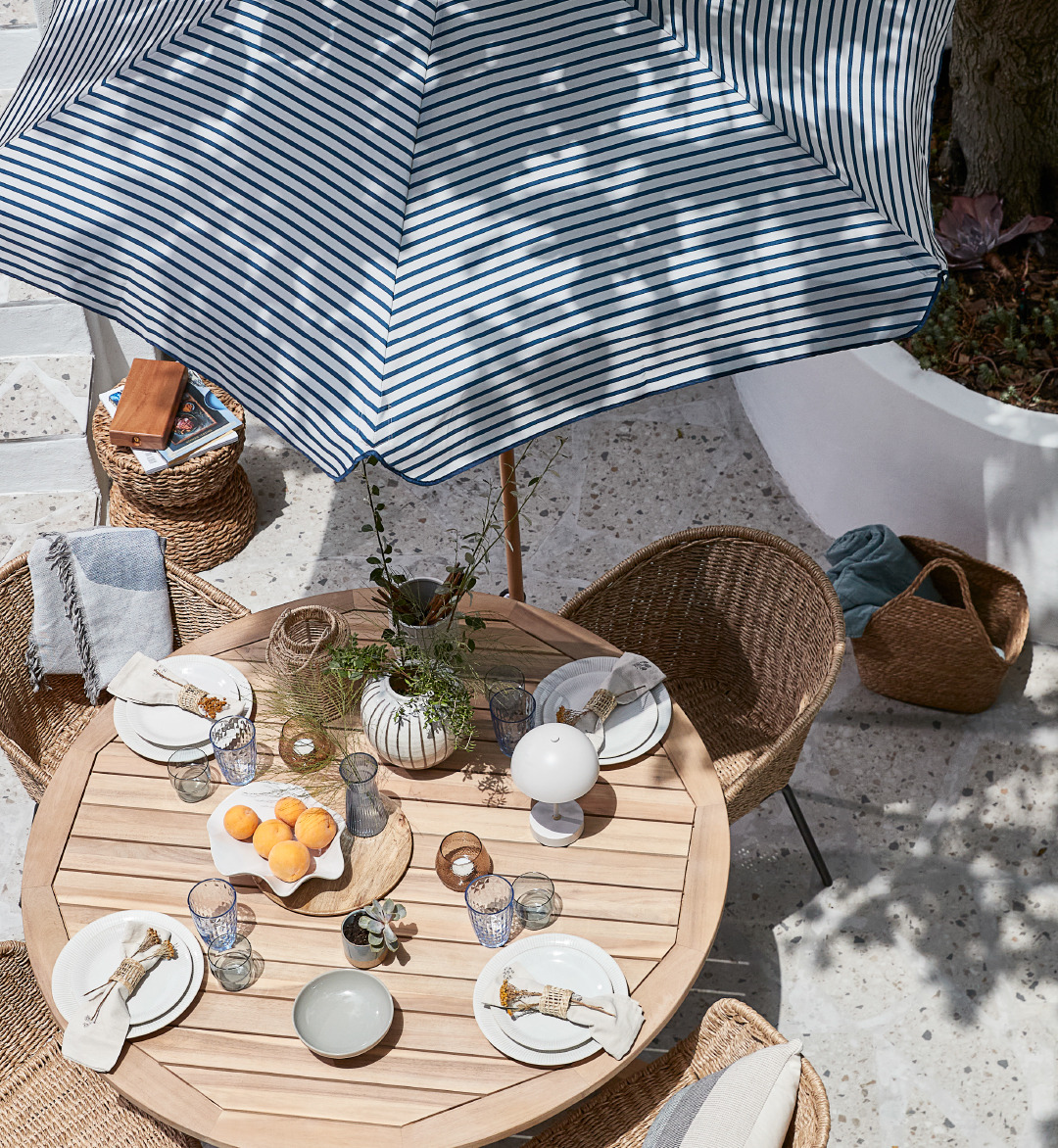 Βεράντα με τραπέζι και καρέκλες κήπου και ριγέ ομπρέλα ηλίου