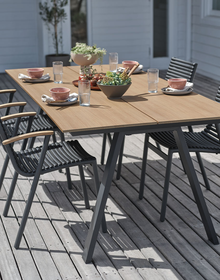 Τραπέζι εξωτερικού χώρου με επιφάνεια από τεχνητό ξύλο και στοιβαζόμενες πλαστικές καρέκλες με μπράτσα από ανακυκλωμένο τικ