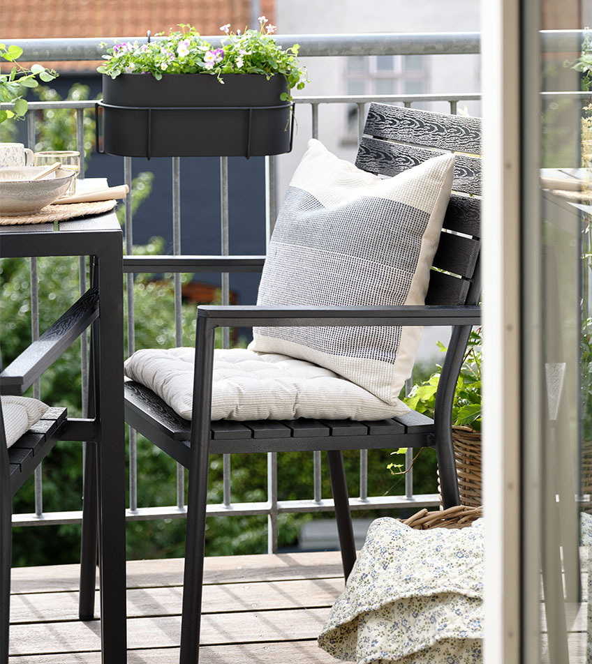Μαύρη στοιβαζόμενη καρέκλα κήπου με μαξιλάρια σε μπαλκόνι