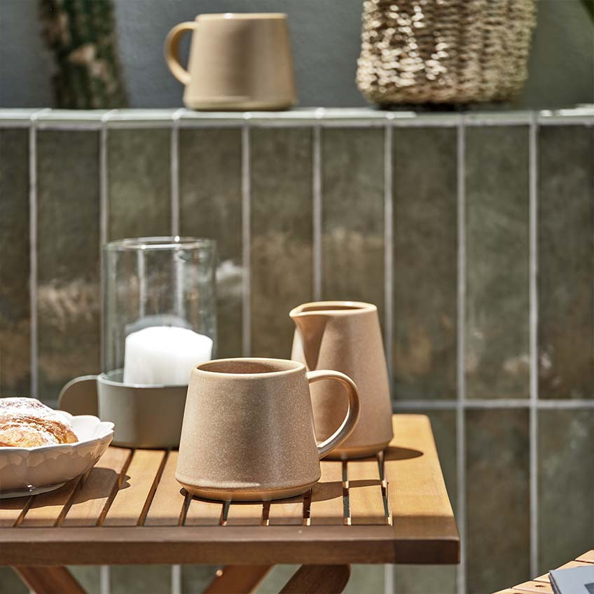 Κούπα καφέ και κανάτα για γάλα σε μικρό ξύλινο τραπέζι κήπου