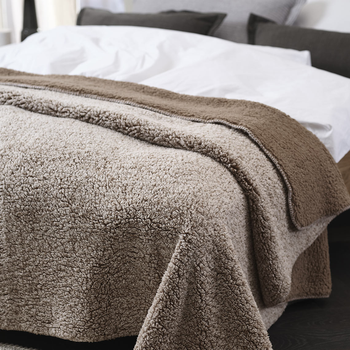 Το φλις ριχτάρι STORFRYTLE  Καφέ φλις ριχτάρι στρωμένο σε κρεβάτι σε υπνοδωμάτιο