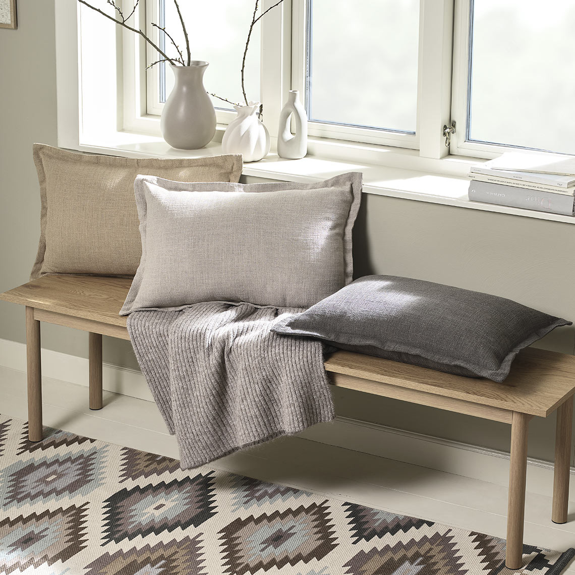 Το κάλυμμα διακοσμητικών μαξιλαριών NATTVIOL είναι διαθέσιμο σε καφέ χρώμα, μπεζ και λάτε Παγκάκι με διακοσμητικά μαξιλάρια σε διάφορα χρώματα