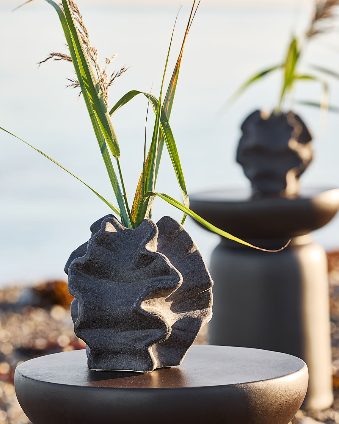 Ένα βάζο με οργανικό σχήμα σε μια τσιμεντένια βάση σε μια παραλία