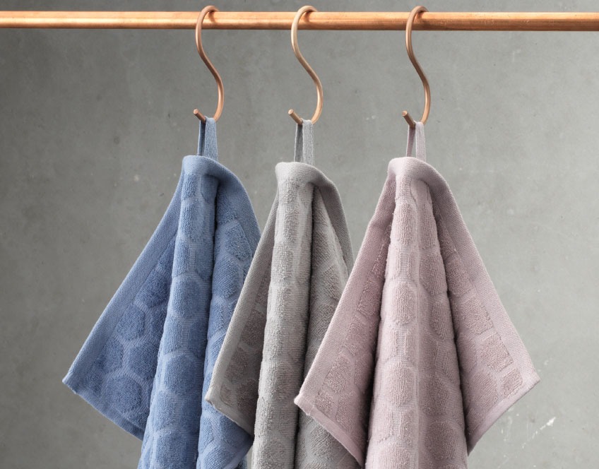 Πετσέτες χεριών μπάνιου σε τρία διαφορετικά χρώματα, οι οποίες κρέμονται σε ράγα
