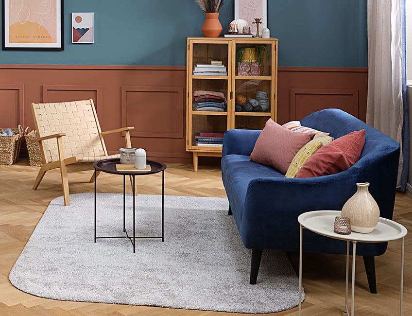 Σαλόνι με χαλί σε ανοιχτό γκρι χρώμα, πολυθρόνα και καναπές με πολύχρωμα μαξιλαράκια