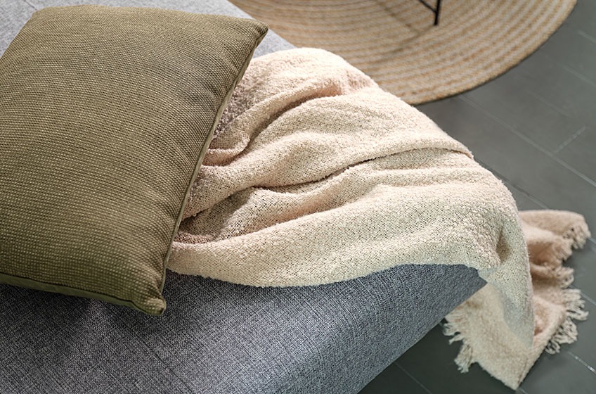 Πράσινο διακοσμητικό μαξιλάρι και πλεκτό ριχτάρι πάνω σε καναπέ