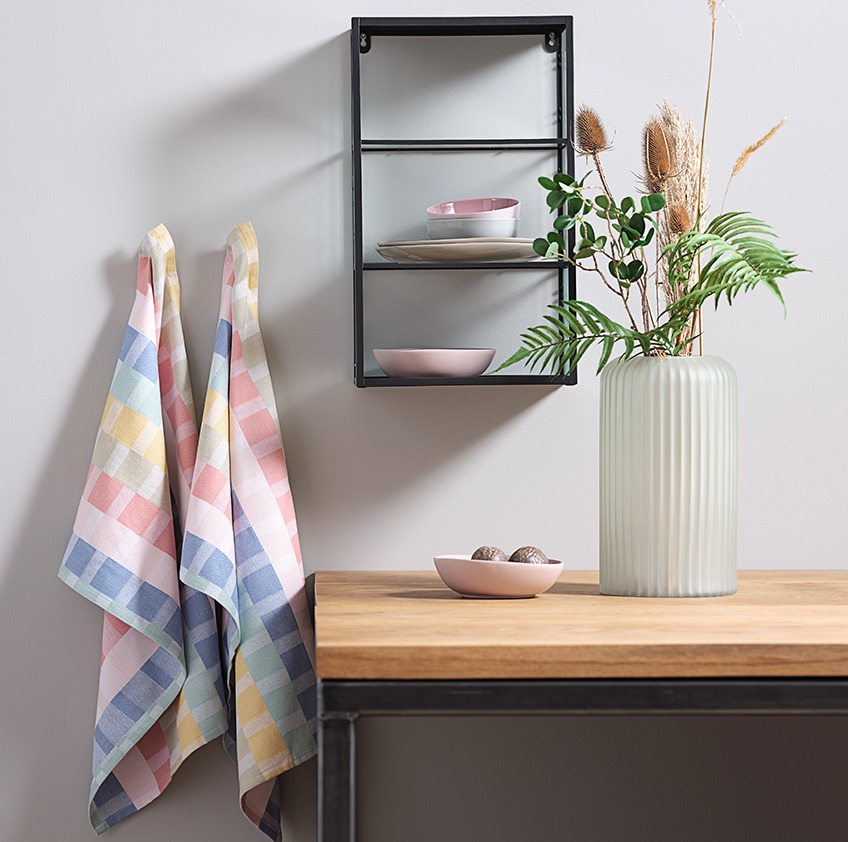 Βαμβακερές πετσέτες κουζίνας που κρέμονται δίπλα από ράφι τοίχου & ένα βάζο πάνω σε τραπέζι