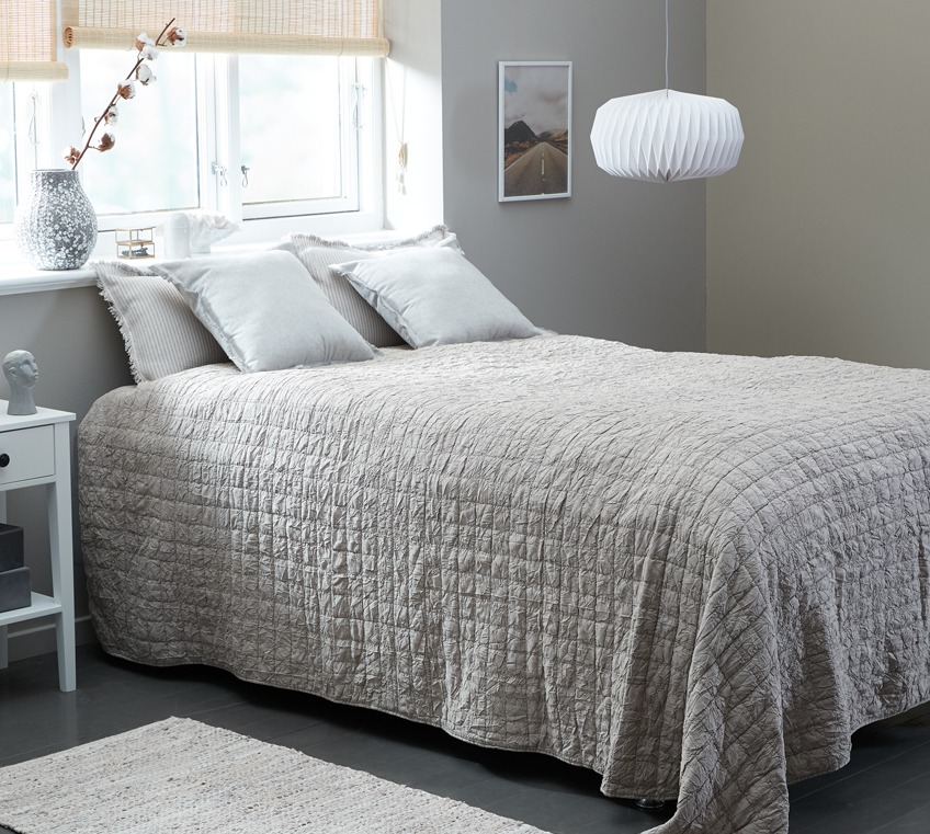 Κρεβάτι στρωμένο με υπέρδιπλο κουβερλί σε απαλό μπεζ χρώμα