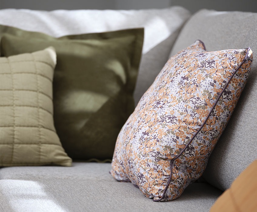 Γκρι καναπές με διακοσμητικά μαξιλάρια σε πράσινο χρώμα και φλοράλ σχέδιο