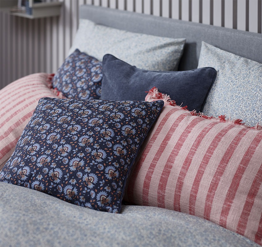 Κρεβάτι με διακοσμητικά μαξιλάρια σε κόκκινες και μπλε αποχρώσεις