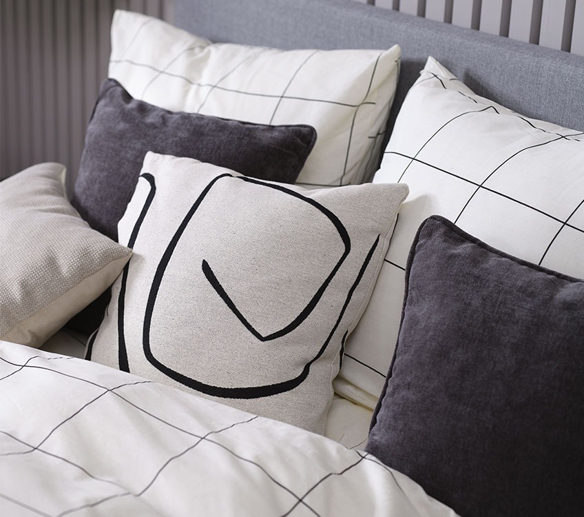 Κρεβάτι στρωμένο με καρό παπλωματοθήκη σε λευκό και μαύρο χρώμα, με διακοσμητικά μαξιλάρια 