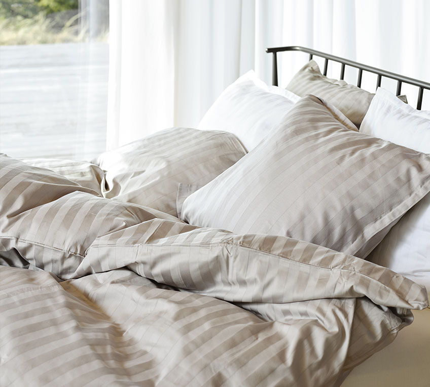 Κρεβάτι με παπλώματα και μαξιλάρια και ριγέ παπλωματοθήκες