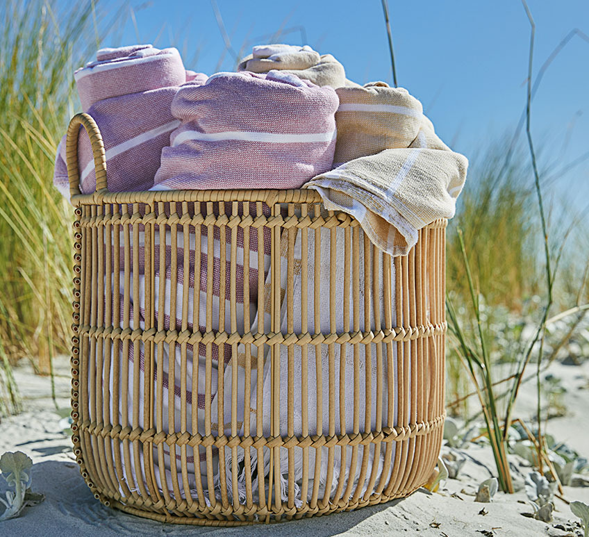 Ψάθινο καλάθι με πετσέτες παραλίας σε αμμουδιά