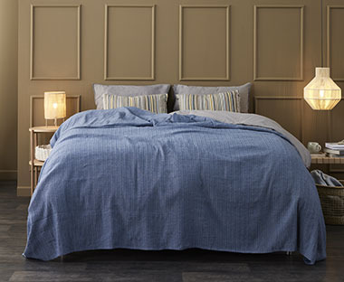 Μπλε κουβερλί στρωμένο σε υπέρδιπλο κρεβάτι