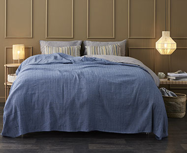 Κουβερλί σε μπλε χρώμα στρωμένο σε κρεβάτι
