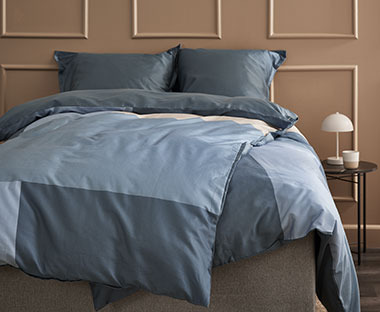 Διπλό σετ παπλωματοθήκης στρωμένο σε κρεβάτι σε μπλε αποχρώσεις με μοτίβα